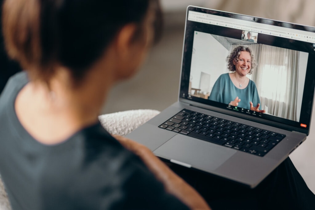 Frau hat ihren Laptop auf dem Schoß und macht ein Anti-Aggressionstraining online.